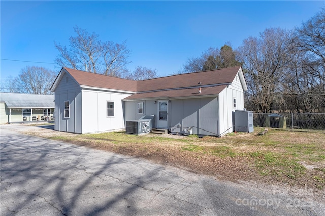 view of front of home featuring board and batten siding, central AC, and fence