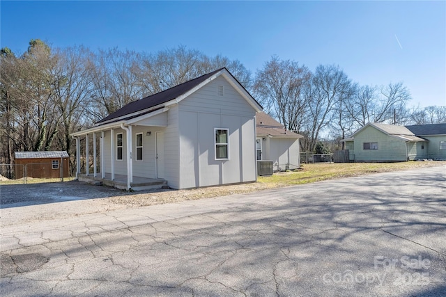 view of property exterior featuring covered porch, fence, and central AC unit