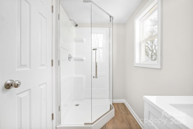 full bath featuring a stall shower, wood finished floors, and baseboards