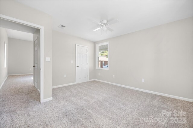 carpeted spare room with baseboards, visible vents, and a ceiling fan