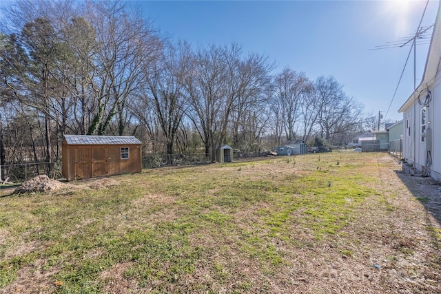 view of yard with a shed, fence, and an outdoor structure