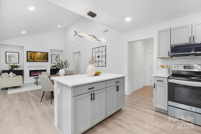 kitchen with stainless steel appliances, gray cabinets, pendant lighting, and light wood-type flooring