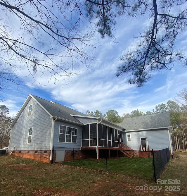 back of house with central AC unit, a sunroom, and a lawn