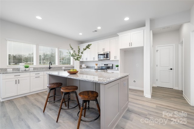 kitchen featuring visible vents, a center island, recessed lighting, appliances with stainless steel finishes, and white cabinetry