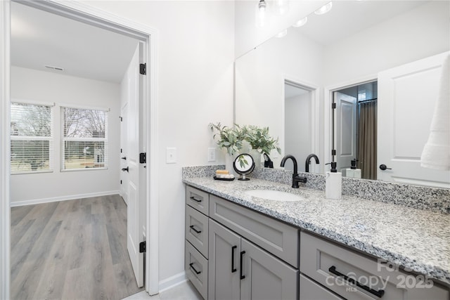 bathroom featuring visible vents, vanity, baseboards, and wood finished floors