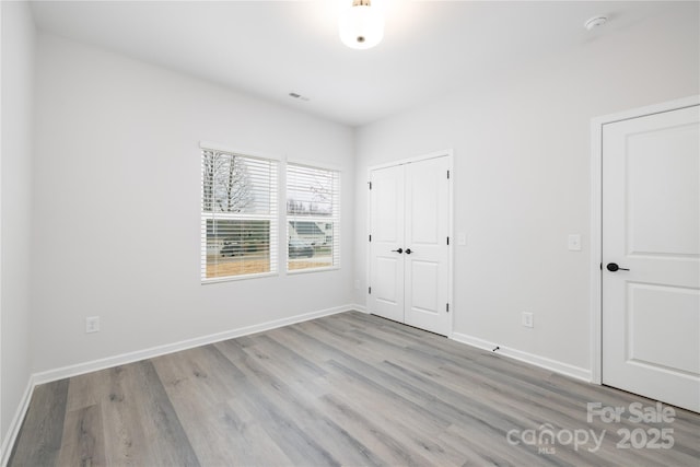 unfurnished bedroom featuring visible vents, baseboards, and light wood-style flooring