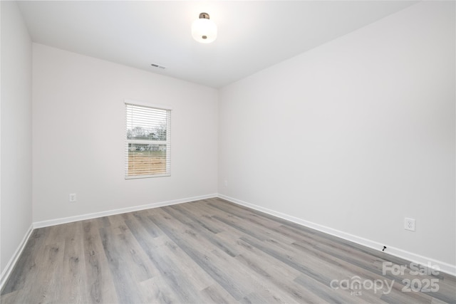 unfurnished room featuring visible vents, baseboards, and wood finished floors