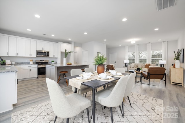 dining area with light wood finished floors, visible vents, and recessed lighting