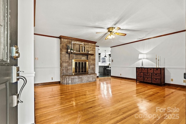 unfurnished living room featuring light hardwood / wood-style flooring, crown molding, a fireplace, and ceiling fan