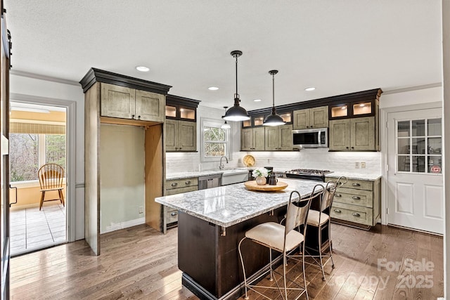 kitchen with a center island, hanging light fixtures, appliances with stainless steel finishes, dark hardwood / wood-style flooring, and light stone countertops