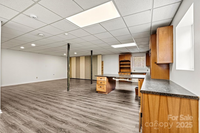 basement with a drop ceiling and dark wood-type flooring