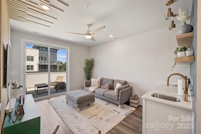 living room with wood-type flooring, sink, and ceiling fan