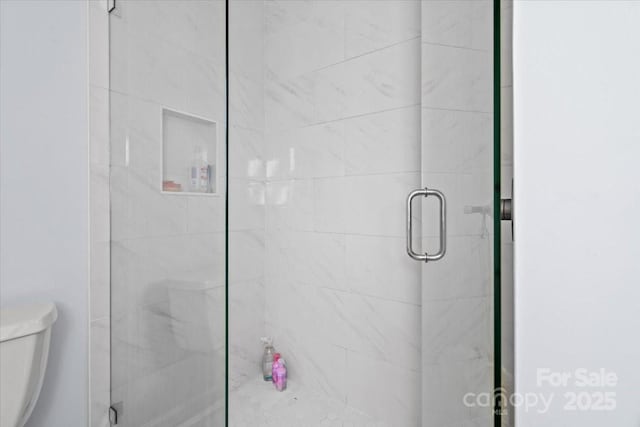 bathroom featuring a shower with shower door and toilet