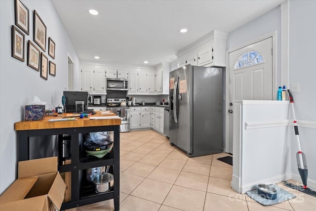 kitchen featuring light tile patterned flooring, appliances with stainless steel finishes, butcher block counters, and white cabinets