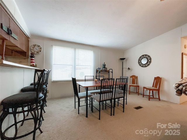 dining room with vaulted ceiling and light carpet