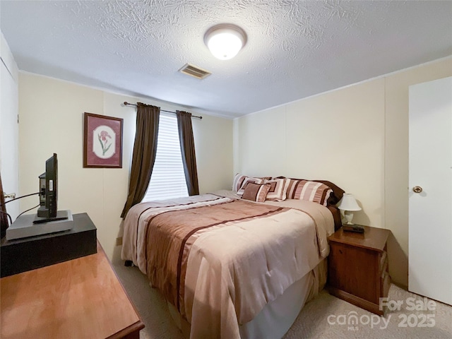 bedroom featuring light carpet and a textured ceiling