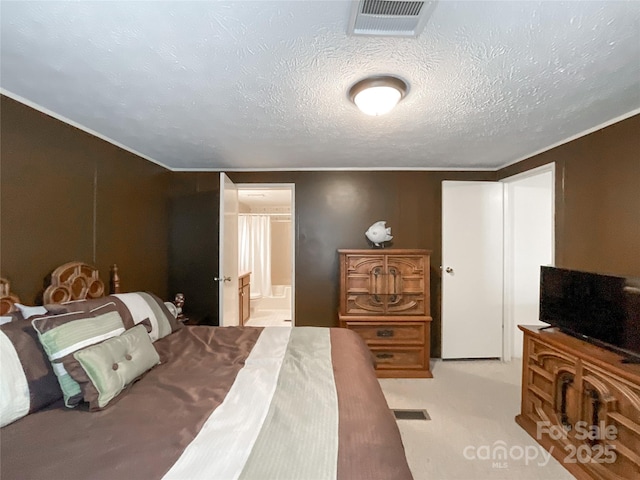 carpeted bedroom with ensuite bathroom and a textured ceiling