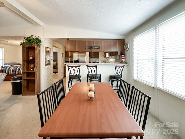 dining room with vaulted ceiling and a textured ceiling