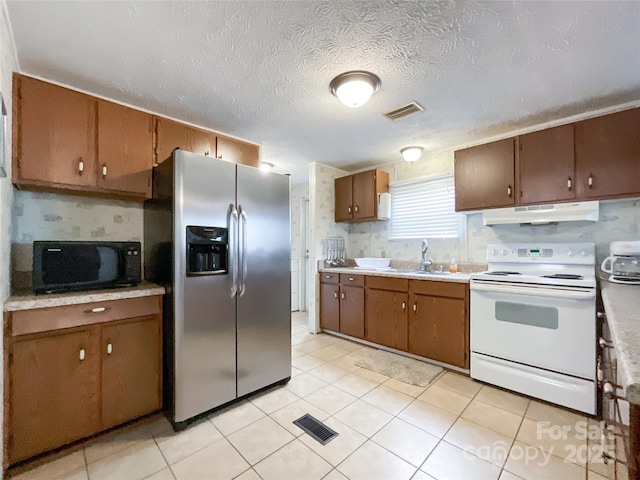 kitchen with stainless steel refrigerator with ice dispenser, sink, a textured ceiling, and electric stove