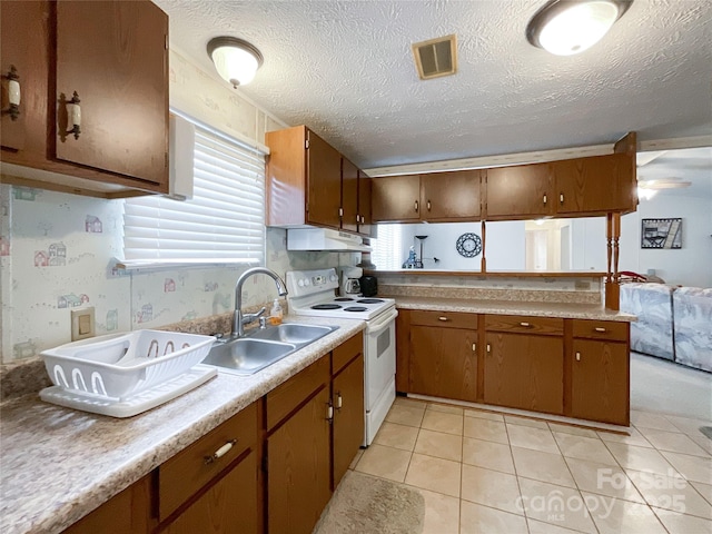 kitchen with electric stove, sink, a textured ceiling, and light tile patterned flooring