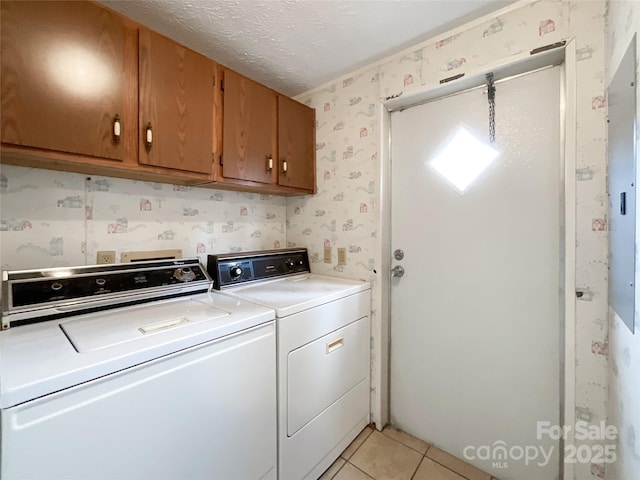 clothes washing area featuring cabinets, light tile patterned floors, a textured ceiling, and independent washer and dryer