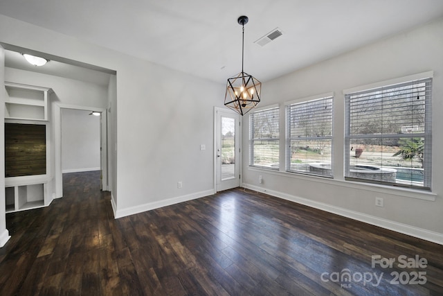 unfurnished dining area featuring dark hardwood / wood-style flooring and a chandelier