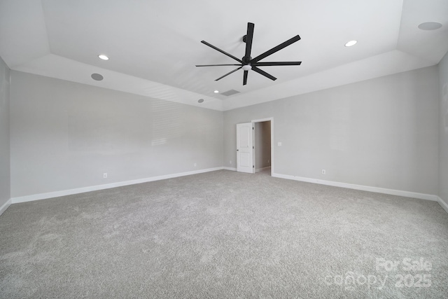 carpeted empty room with ceiling fan, lofted ceiling, and a raised ceiling