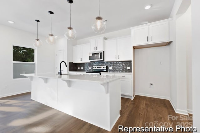 110 Shay Crossing Rd Unit 1P, Salisbury, NC 28144 - kitchen featuring appliances with stainless steel finishes, decorative backsplash, dark wood-style floors, a kitchen breakfast bar, and an island with sink