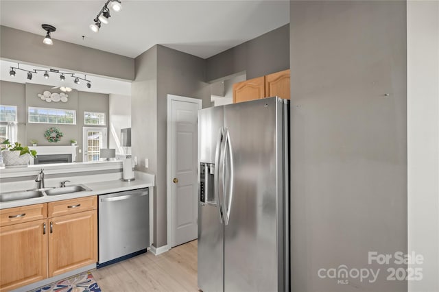 kitchen featuring stainless steel appliances, sink, light brown cabinetry, and light hardwood / wood-style floors