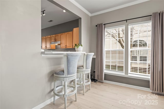 kitchen featuring crown molding, light hardwood / wood-style flooring, and a breakfast bar