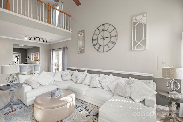 living room with a high ceiling, crown molding, track lighting, and ceiling fan