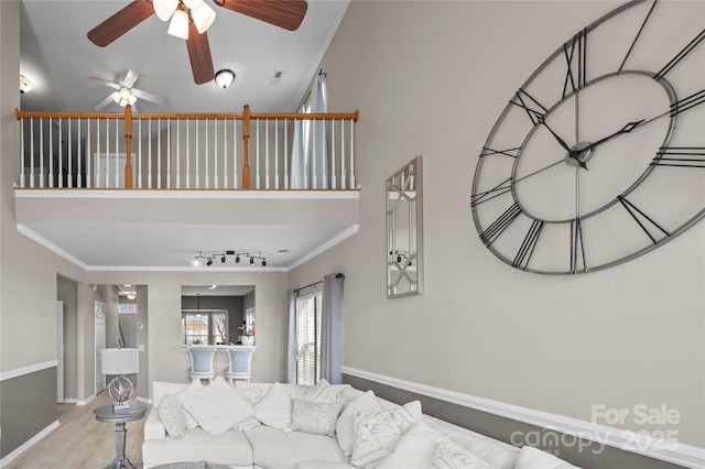 living room featuring ornamental molding, a towering ceiling, track lighting, and light hardwood / wood-style floors