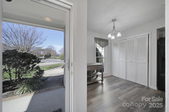 foyer entrance featuring an inviting chandelier, a textured ceiling, and hardwood / wood-style floors