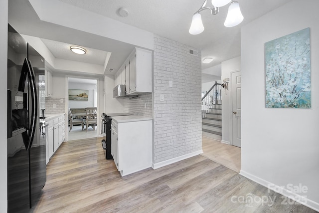 kitchen featuring white cabinetry, black appliances, light hardwood / wood-style flooring, and decorative light fixtures