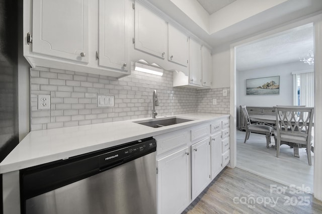 kitchen featuring light wood-type flooring, sink, dishwasher, white cabinets, and decorative backsplash