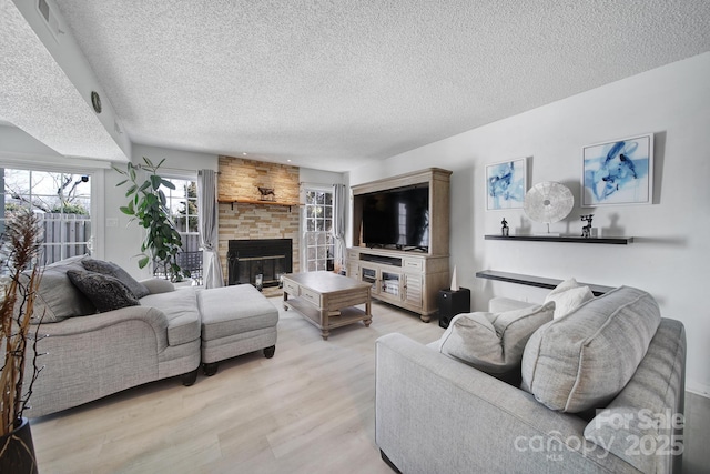 living room with light hardwood / wood-style floors, a textured ceiling, and a fireplace