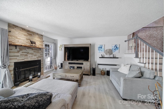 living room with light hardwood / wood-style flooring, a textured ceiling, and a fireplace