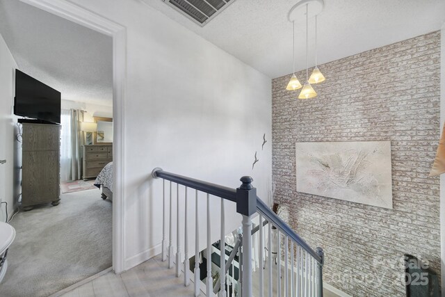 hallway featuring light colored carpet and a textured ceiling