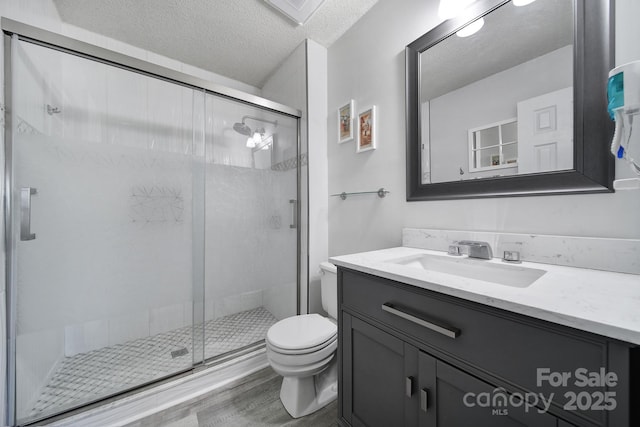 bathroom with toilet, a textured ceiling, walk in shower, hardwood / wood-style floors, and vanity