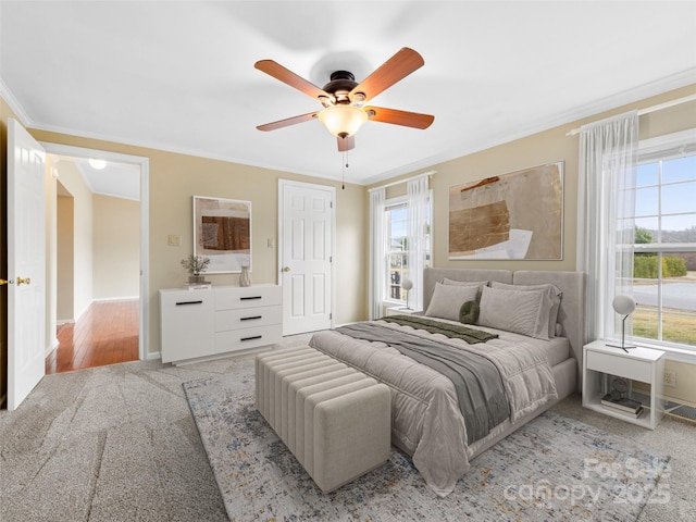 bedroom featuring ornamental molding, light colored carpet, and ceiling fan