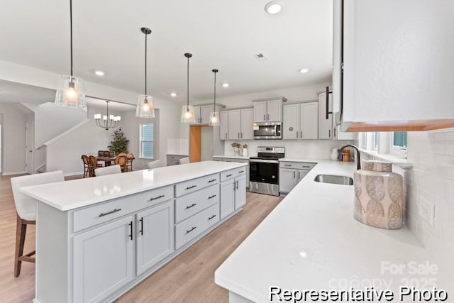 kitchen with stainless steel appliances, sink, a breakfast bar, and decorative light fixtures