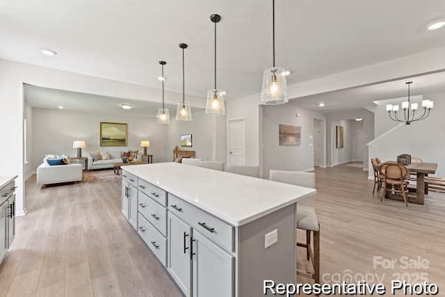 kitchen with hanging light fixtures, light wood-type flooring, a breakfast bar area, and a kitchen island