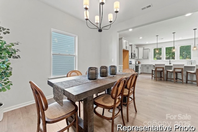 dining area with a notable chandelier and light hardwood / wood-style flooring