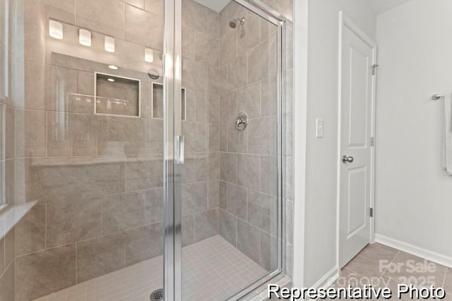 bathroom with a shower with shower door and tile patterned floors