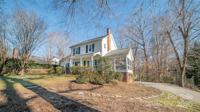 view of home's exterior with a lawn, a porch, and a sunroom