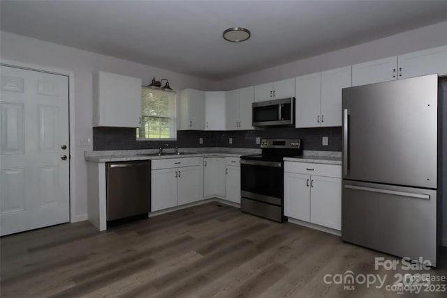 kitchen featuring sink, dark wood-type flooring, white cabinetry, stainless steel appliances, and tasteful backsplash