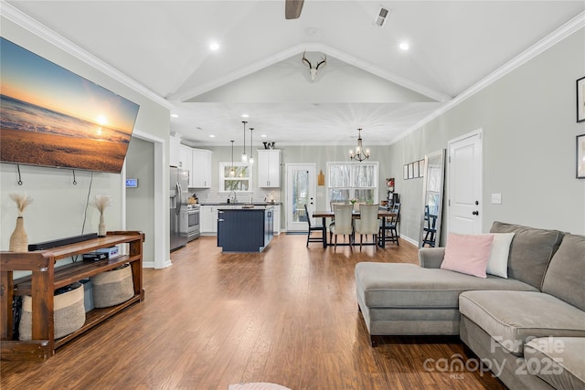 living room featuring wood-type flooring, vaulted ceiling, ornamental molding, and an inviting chandelier