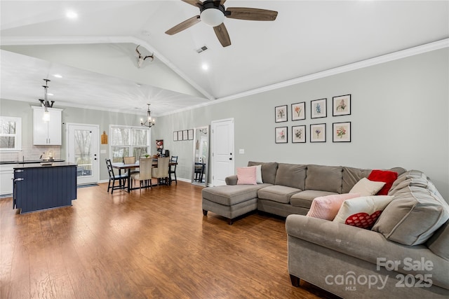 living room featuring hardwood / wood-style flooring, vaulted ceiling, ornamental molding, and ceiling fan with notable chandelier