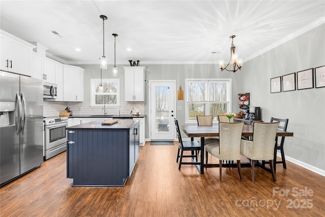 kitchen featuring tasteful backsplash, white cabinetry, hanging light fixtures, a center island, and stainless steel appliances