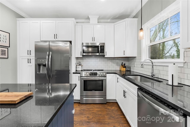 kitchen with sink, white cabinetry, dark stone countertops, appliances with stainless steel finishes, and pendant lighting